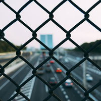 フェンス越しに見る高速道路を走行する車と都市景観の写真