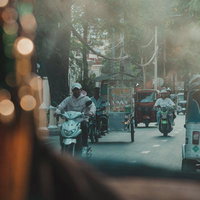 カンボジアの都市部でよく見られるトゥクトゥクやバイクが走る街道の写真