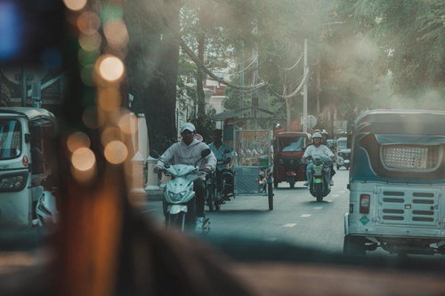 カンボジアの都市部でよく見られるトゥクトゥクやバイクが走る街道