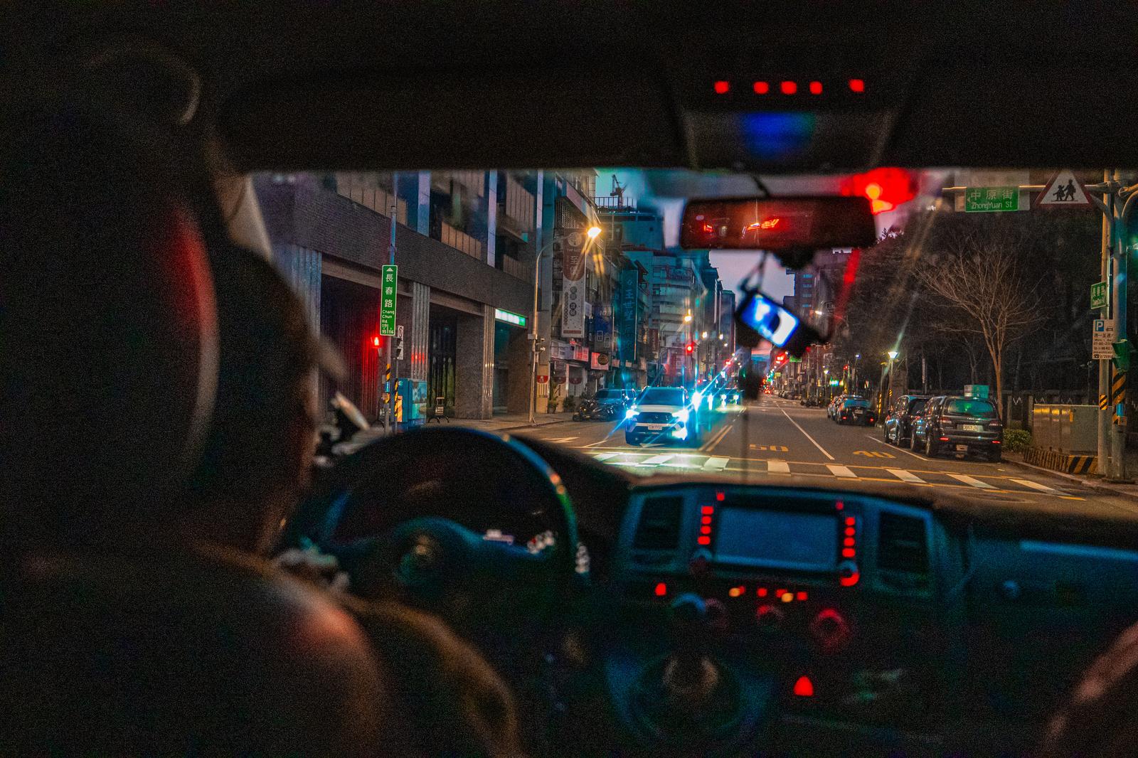対向車のヘッドライトが眩しい夜の市街地を走る車内からの前方視点