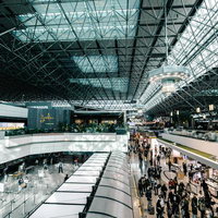 ガラス天井から採光される国際空港の出発ロビーの写真