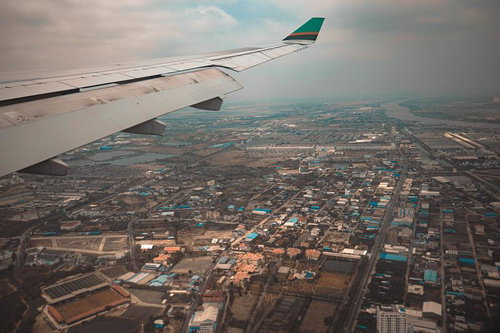 飛行機の窓際席から撮影したカンボジア上空の都市風景と主翼