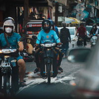 カンボジアの細い市街地の通りをバイクが走り抜けるの写真
