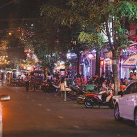 カンボジアの繁華街にある屋台や飲食店が並ぶネオンが輝く夜の通りの写真