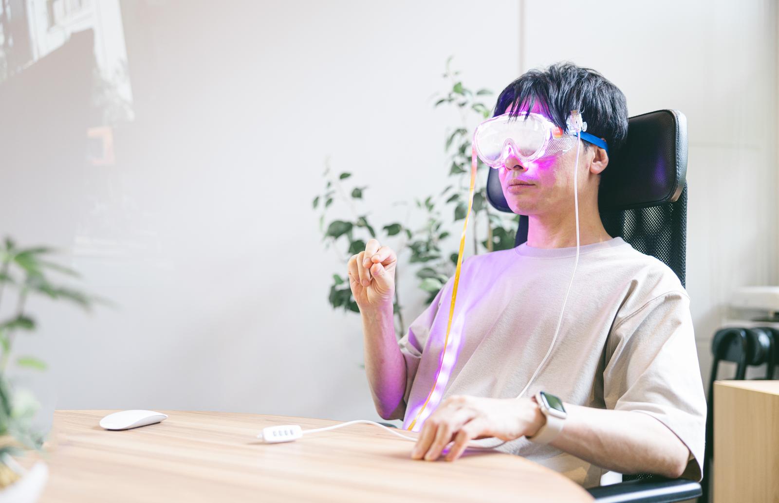 ピンク色のARゴーグルを装着してパソコンを操作する男性［モデル：金子周平］