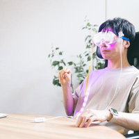 ピンク色のARゴーグルを装着して仮想世界で業務をこなす男性の写真