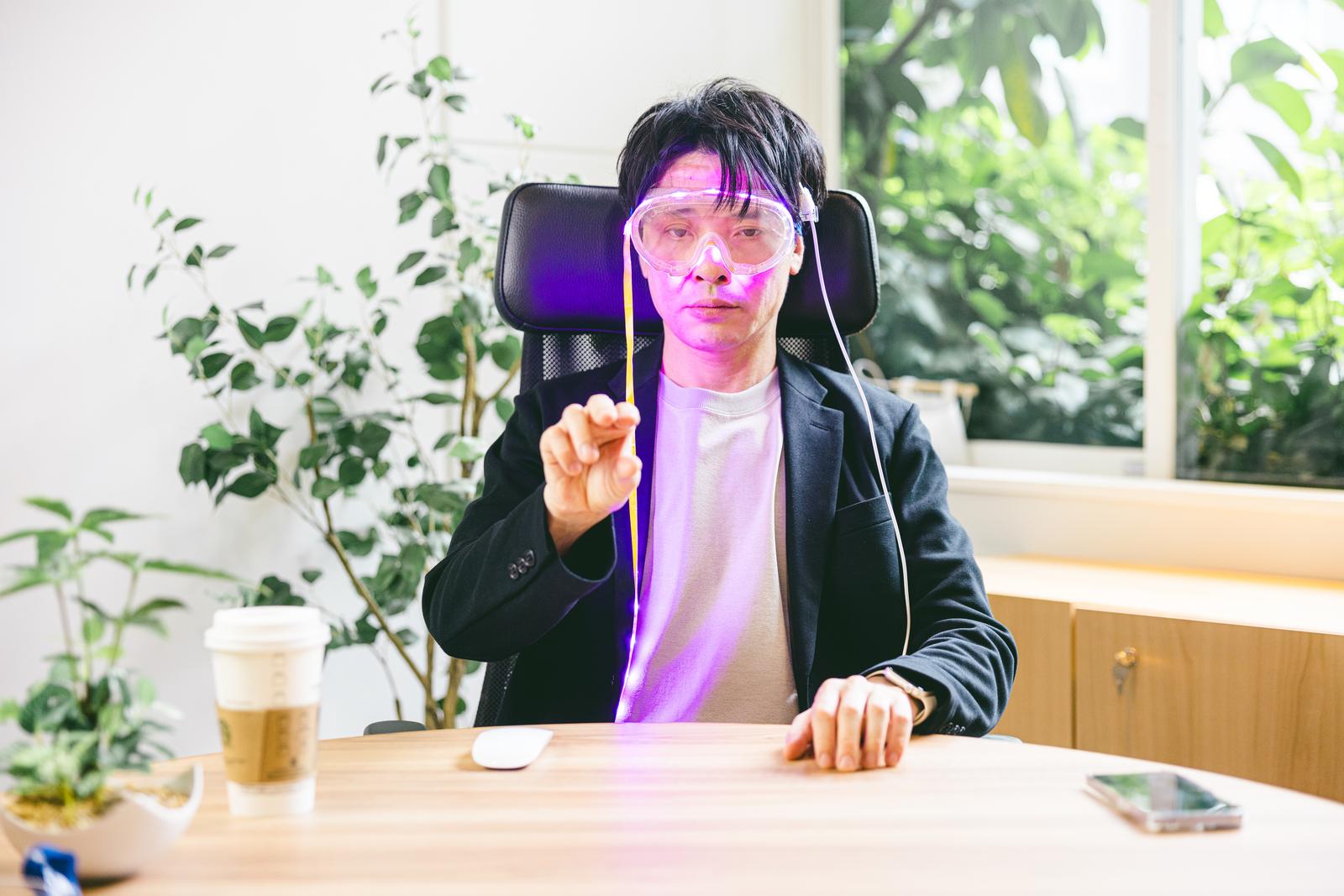 ARゴーグルを装着してジェスチャー操作する男性起業家がオフィスで前方を指している［モデル：金子周平］