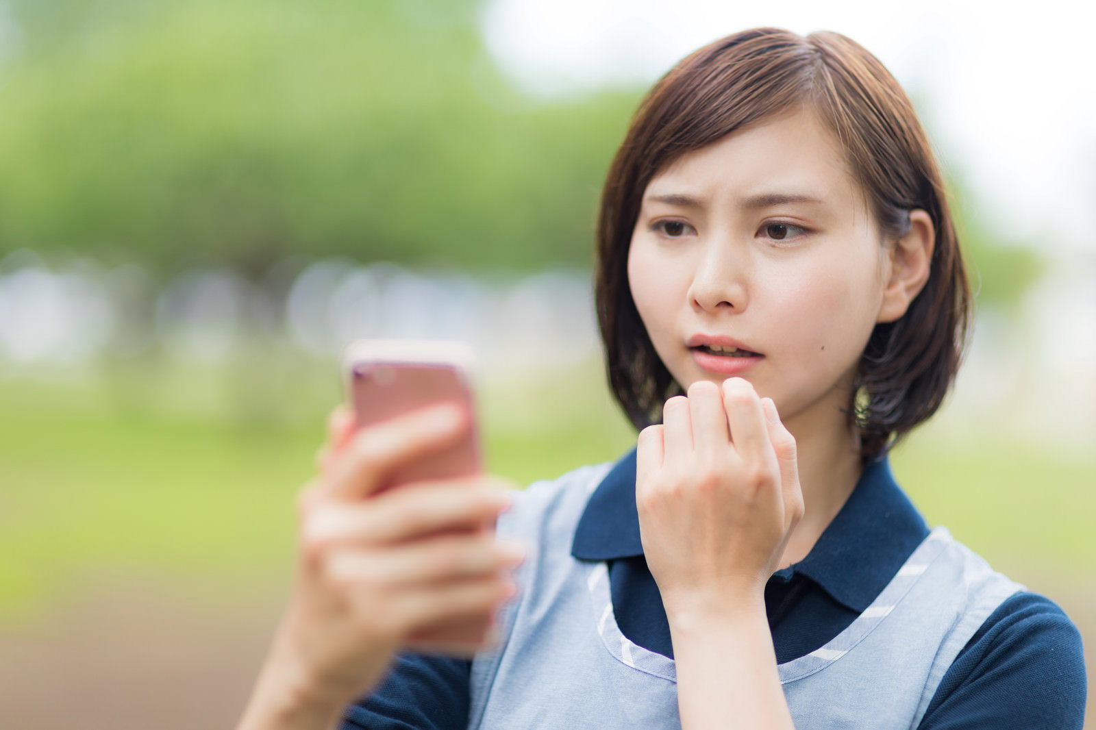 スマホを見て驚く介護士の女性［モデル：yumiko］