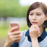 スマホを見て驚く介護士の女性の写真