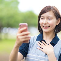 見つかって安堵の表情を浮かべるスマートフォンを確認する女性介護士の写真