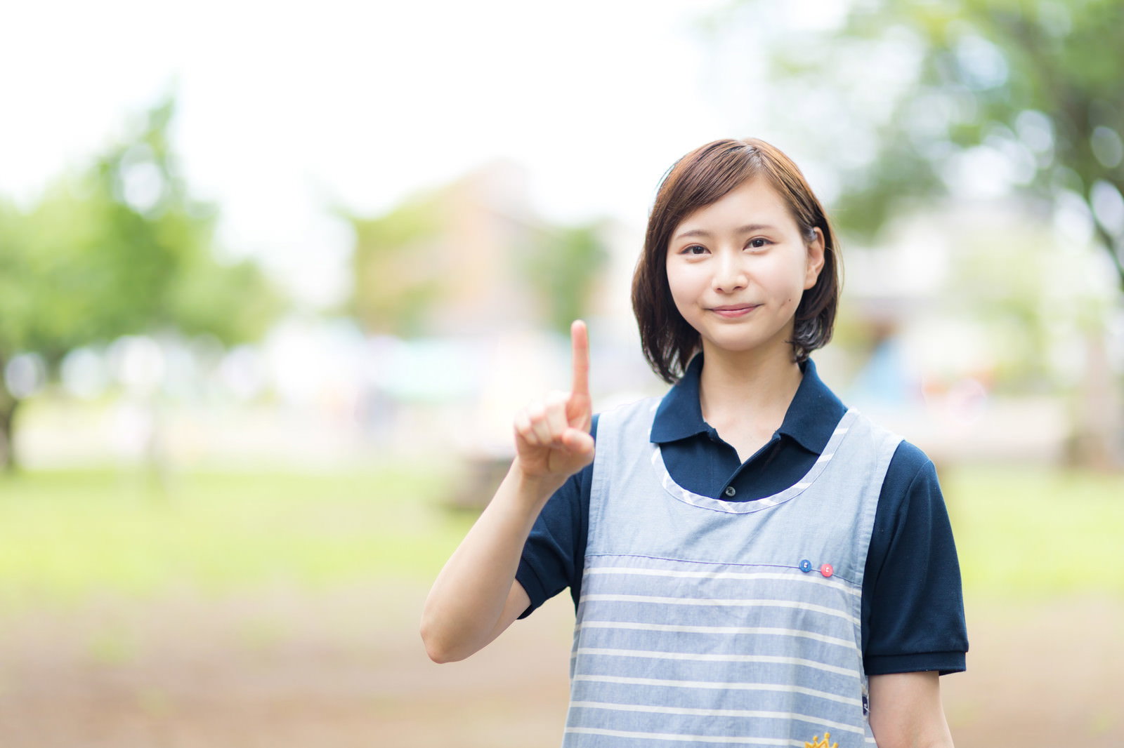 人差し指を立てて笑顔でポーズをとる制服姿の女性［モデル：yumiko］