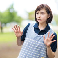 両手を広げて驚く女性ヘルパー、介護現場のトラブル対応の写真