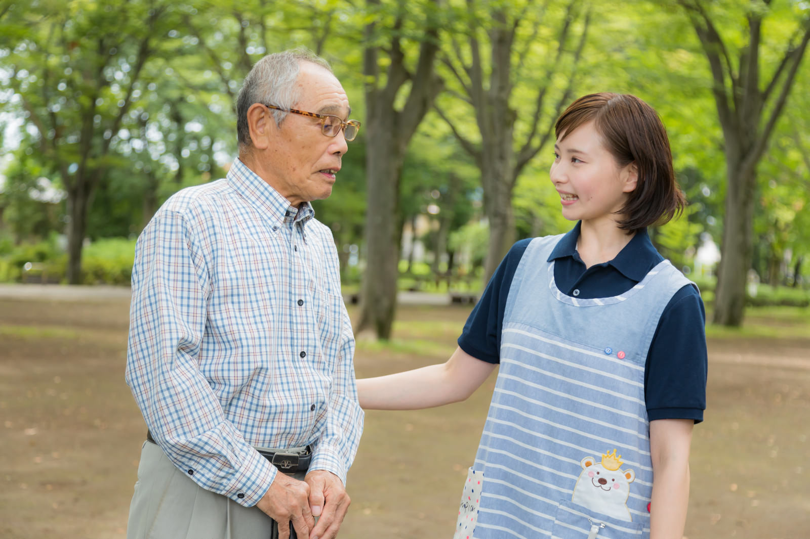 公園のベンチで寄り添うお爺さんと女性ヘルパー