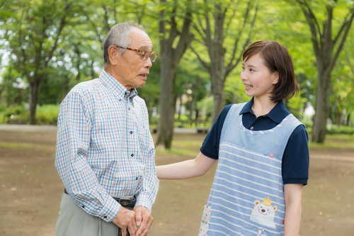 公園のベンチで寄り添うお爺さんと女性ヘルパー