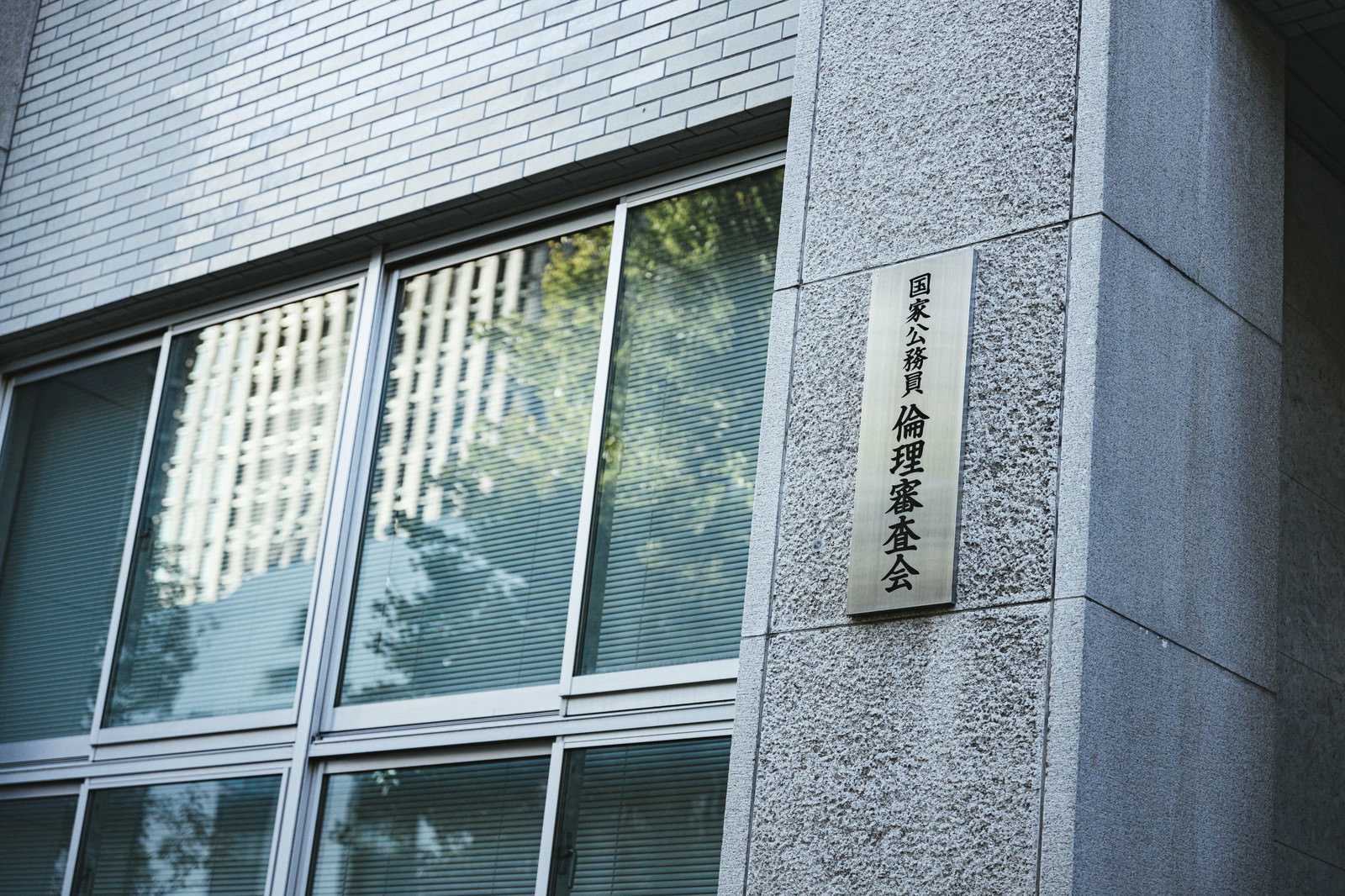 グレーの建物外壁に設置された国家公務員倫理審査会の銘板