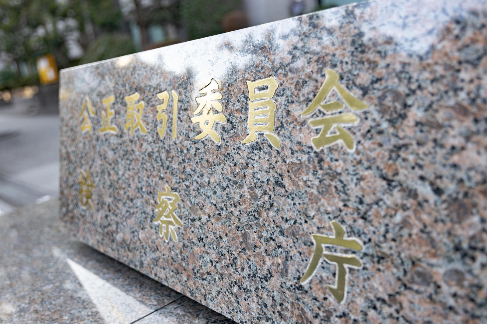 灰色の石材に金色の文字で刻まれた公正取引委員会と検察庁の銘板