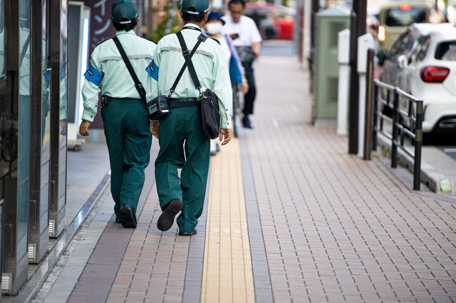 Rear view of two parking enforcement officers walking on a sidewalk