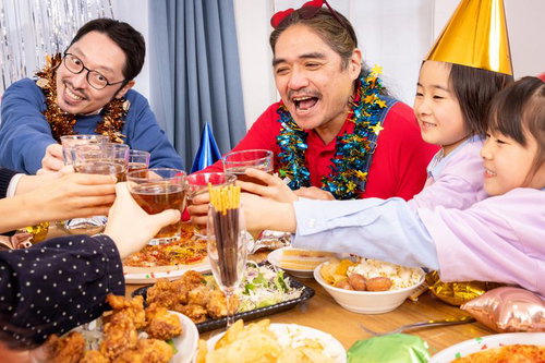 テーブルを囲んで乾杯する家族の団欒シーン