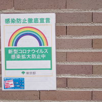 新型コロナウイルス感染拡大防止中のビラ、レンガ壁に掲示の写真