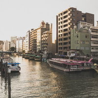 屋形船が停泊している河川沿いの夕暮れ時の街並みの写真