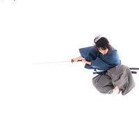 一閃の刀を両手で構えて跳躍する袴姿の男性の写真