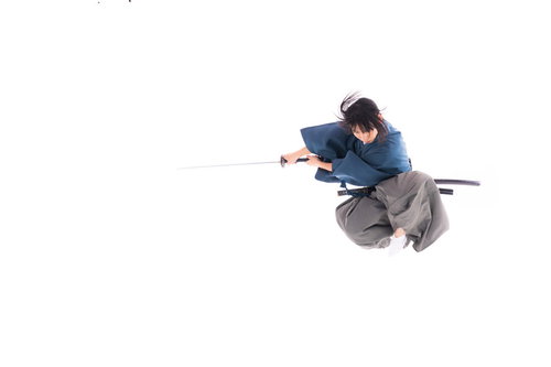 一閃の刀を両手で構えて跳躍する袴姿の男性