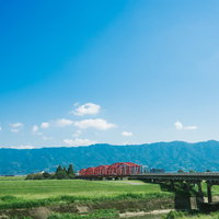 片の瀬橋を走る赤い電車と田園風景（大刀洗）の写真