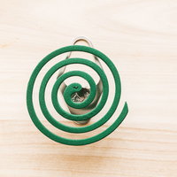 木製テーブルに置かれた線香立てのうずまき線香の写真