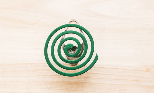 木製テーブルに置かれた線香立てのうずまき線香