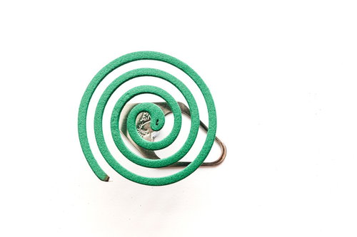 使用中の緑色渦巻き蚊取り線香と白い煙が立ちのぼる様子