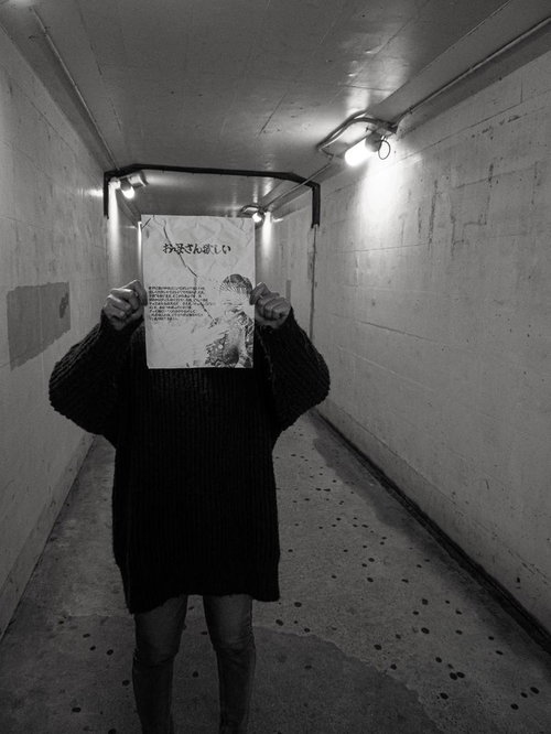 地下通路で怪文書を掲げる黒いセーターの人物