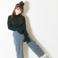 嬉しくて心が踊る緑のトップスの女性、ワイドパンツを合わせたハッピースタイルの写真