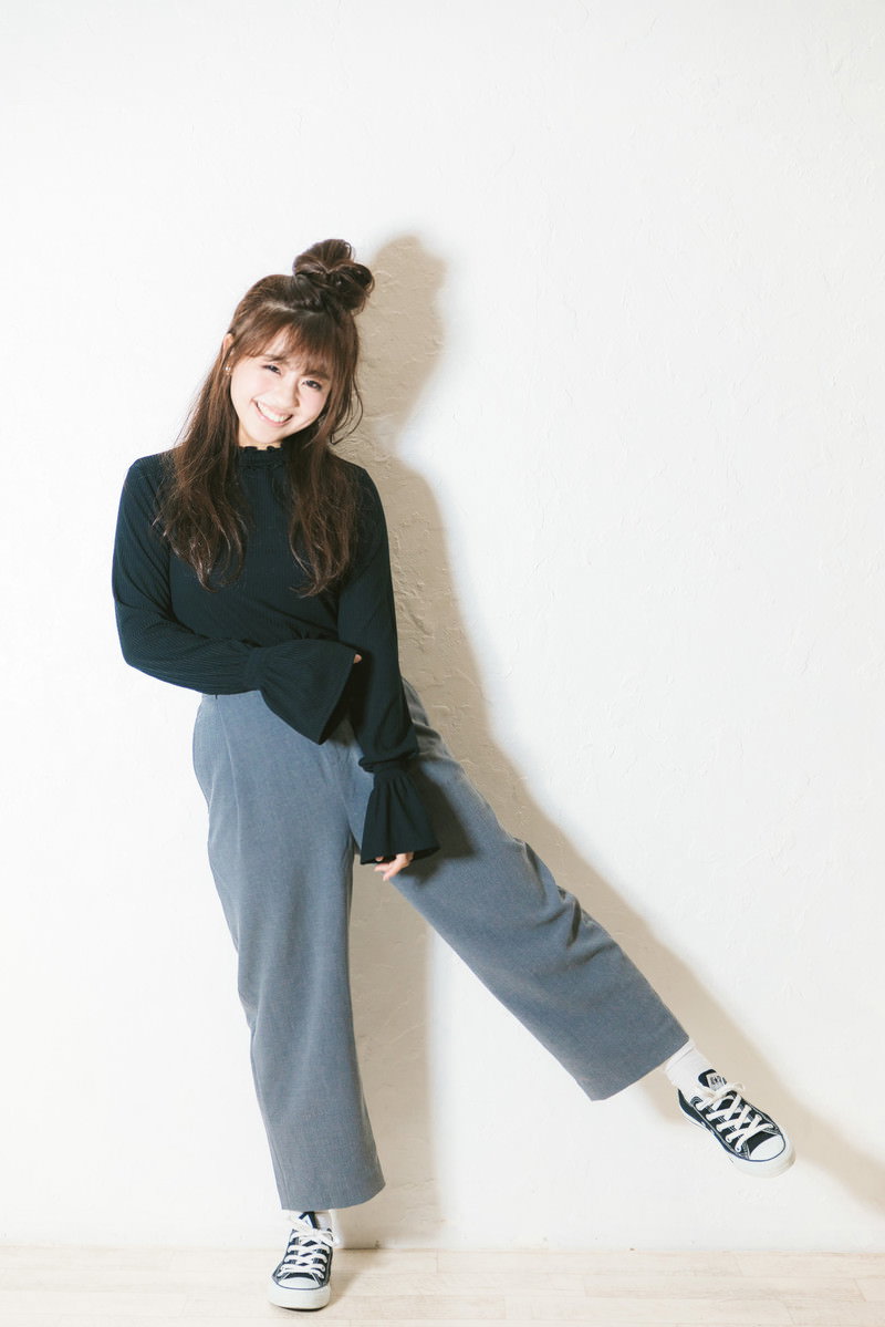 緑のトップスと水色のワイドパンツを着て嬉しそうに笑顔を見せる女性［モデル：河村友歌］