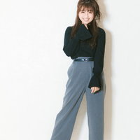 黒いトップスと水色のワイドパンツを着た笑顔の女子大生の写真