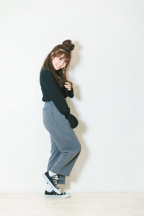 秋物の緑色トップスとワイドパンツを着た小柄な女性の笑顔