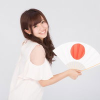 日本一の笑顔で日の丸の扇子を掲げる若い女性のポートレートの写真