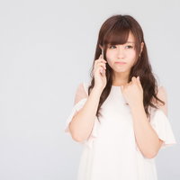 残念なお知らせを聞いてスマホ通話中に落ち込む女性の写真