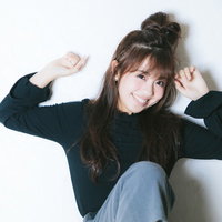 壁にもたれかかる元気な女性の笑顔とポーズの写真