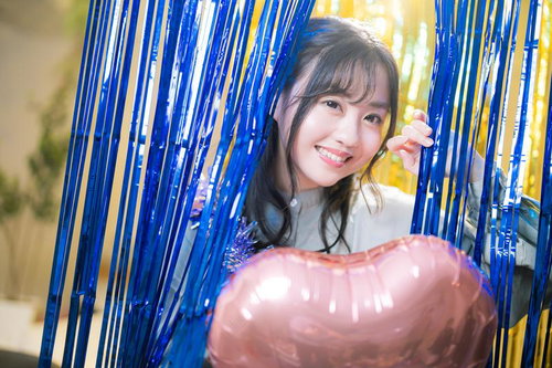 青と黄色の装飾の中から顔を出して微笑む女性