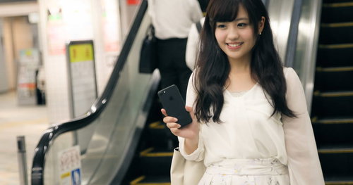 財布や定期券を出さずにスマートフォンで駅の改札を出る女性