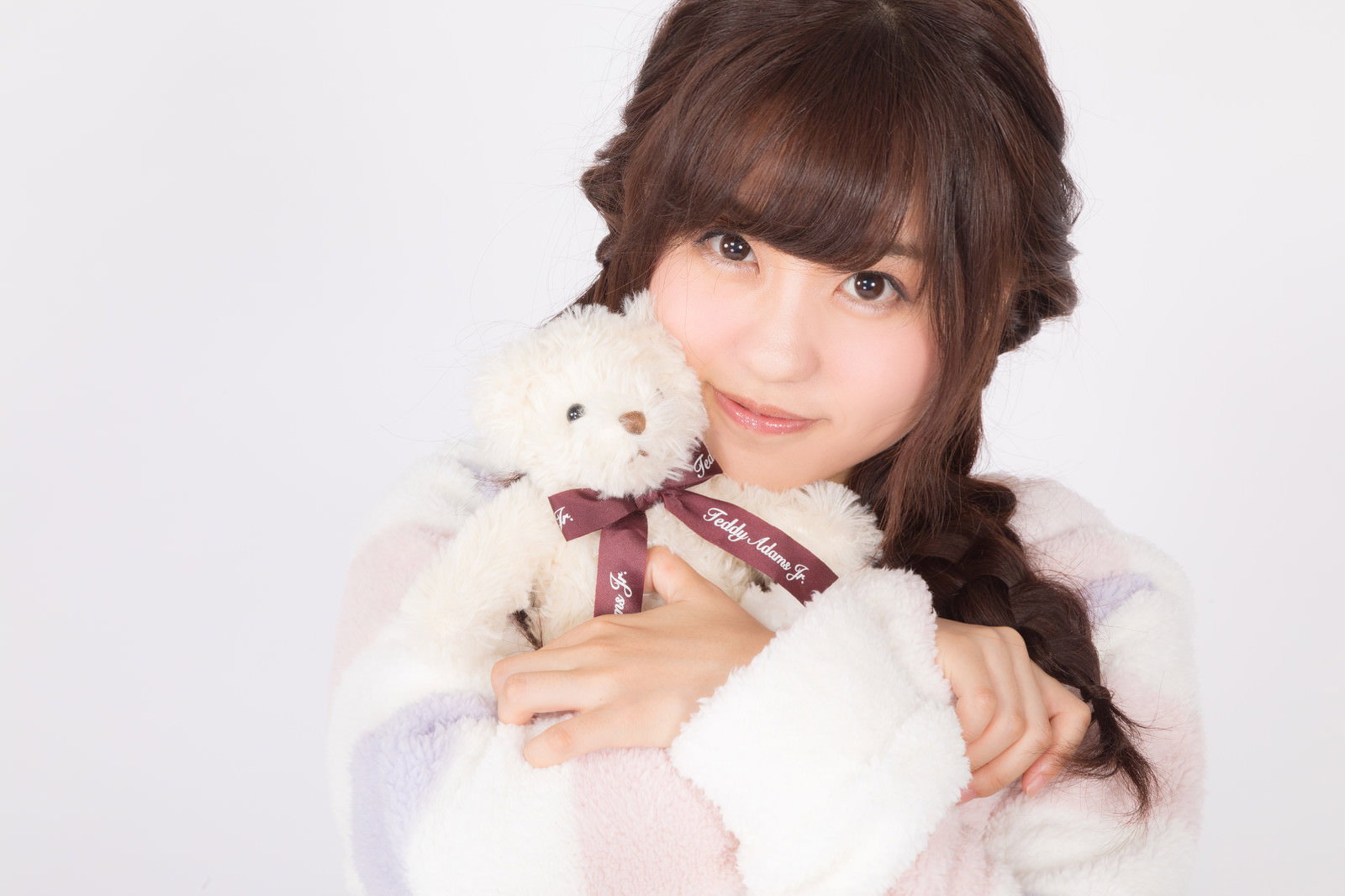 白いパジャマを着た三つ編みの女性がテディーベアを抱きしめている［モデル：河村友歌］