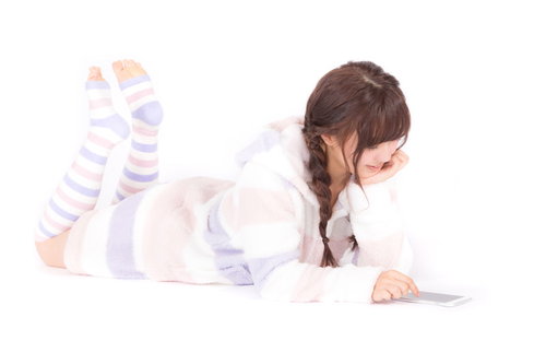 パジャマ姿で横になりながらスマホアプリを楽しむ女性