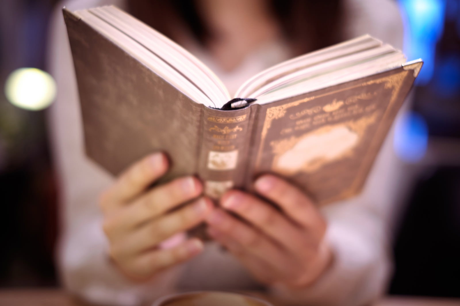 夜の街中で洋書を開いて読んでいる女性