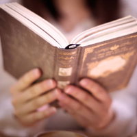 夜の街中で洋書を持つ女性が読書する風景の写真