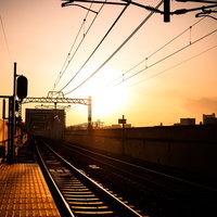 夕焼け空の下に続く駅のホームと線路の写真