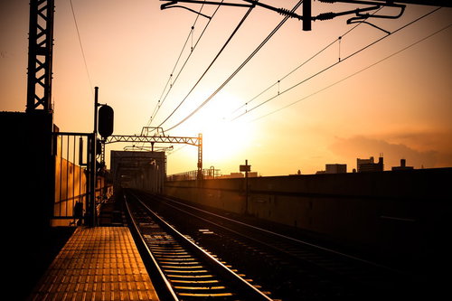 夕焼け空の下に続く駅のホームと線路