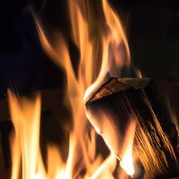 暗い場所で黄色とオレンジの炎が上がる燃える薪の篝火の写真
