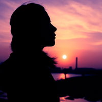 紫色の夕焼けに浮かぶ女性のシルエット、夕暮れの景色の写真