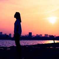 夕焼けのスカイラインに立つ女性のシルエットの写真