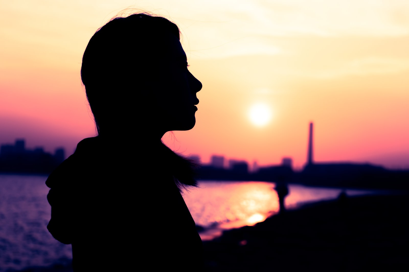 夕日を背景に女性の横顔のシルエットが美しく映える夕暮れの風景［モデル：Mizuho］